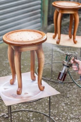 Carpenter is covering stool by lacquer