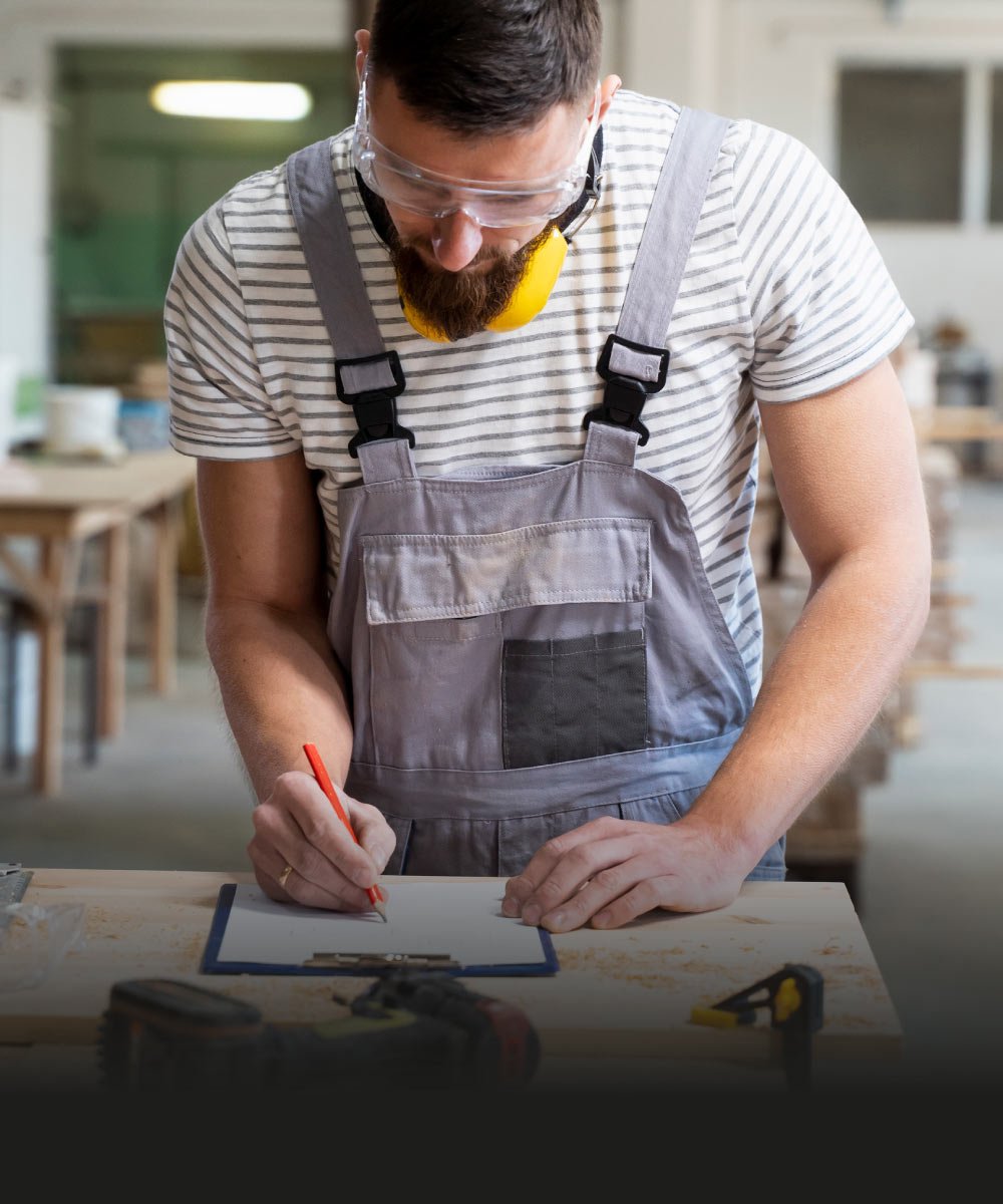 Handwerker zeichnet präzise auf einem Werkstatttisch