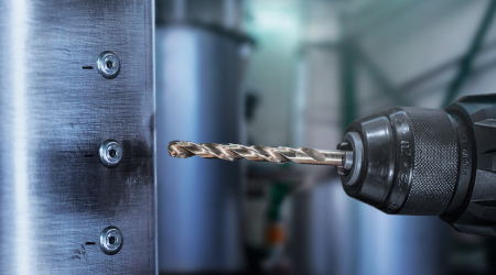 Bohrer durchdringt Metallplatte – präzises Bohren in der Werkstatt