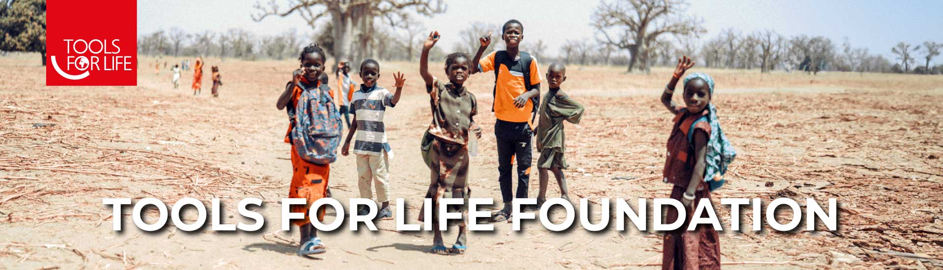 Kinder in ländlichem Afrika winken, unterstützt von der Tools for Life Stiftung