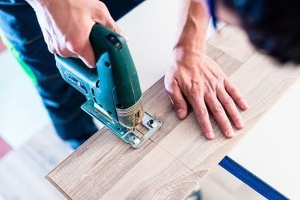 DIY worker cutting wooden panel with jig saw